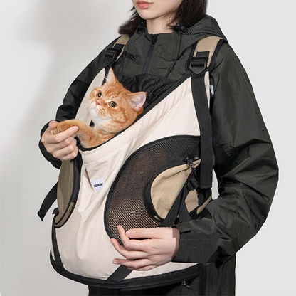 Person wearing a black jacket with a beige pet carrier holding an orange cat on a white background